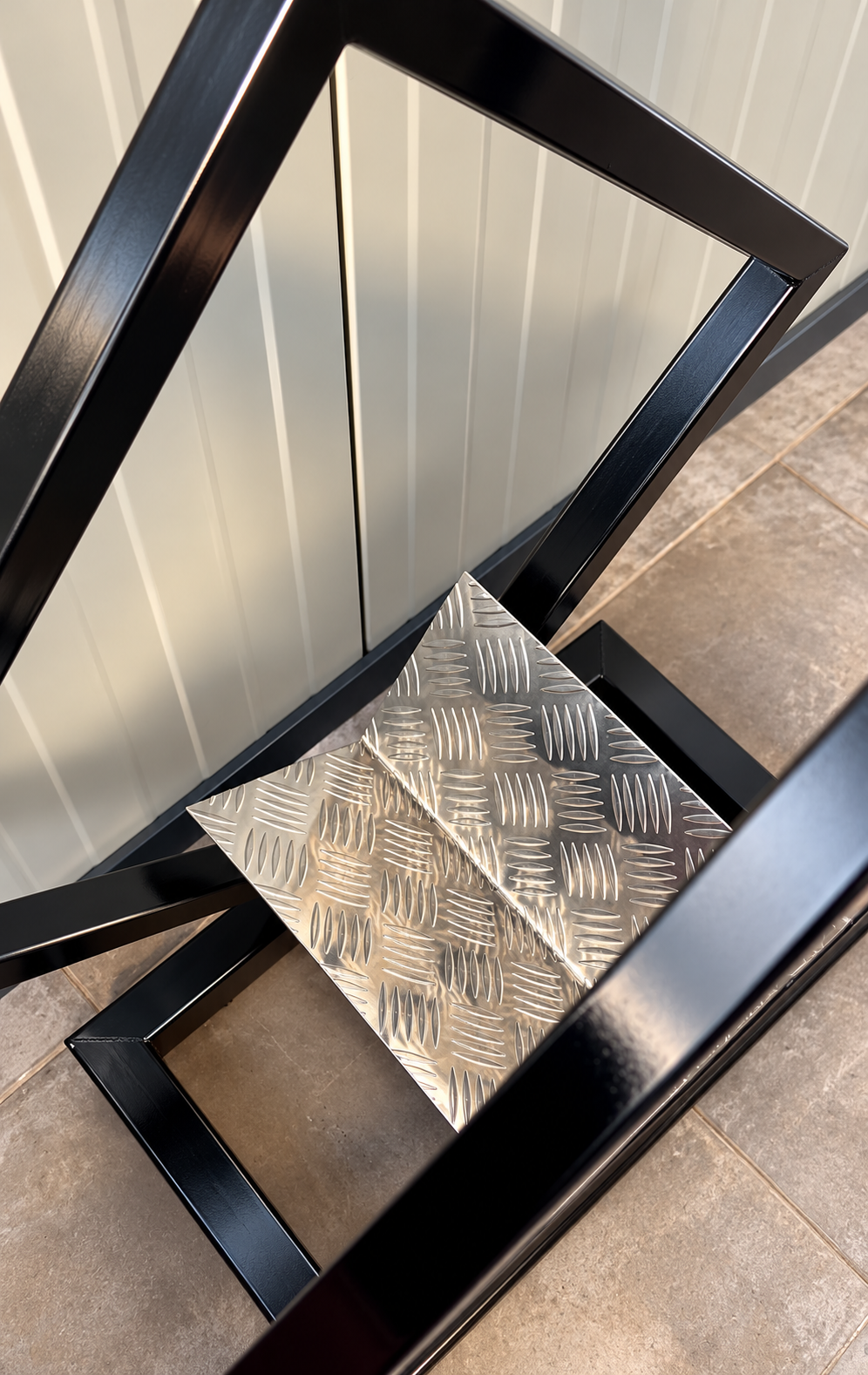 Ajout d’une tôle en aluminium damier au fond du porte-bûches DIY pour retenir les écorces et les débris de bois.